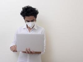 homme d'affaires en masque médical travaille sur ordinateur portable à la maison photo