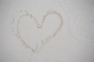 coeurs dessinés sur le sable d'une plage photo