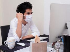jeune garçon asiatique portant un masque facial travaillant sur un ordinateur portable pendant la pandémie de coronavirus photo