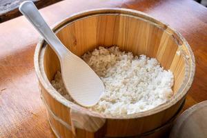 délicieux riz nature cuit dans un grand bol en bois prêt à manger avec une cuillère à spatule de riz blanc à la table du restaurant, gros plan, mode de vie. photo