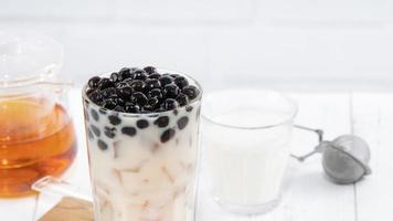 thé au lait à bulles avec garniture de perles de tapioca, célèbre boisson taïwanaise sur fond de table en bois blanc dans un verre à boire, gros plan, espace de copie photo