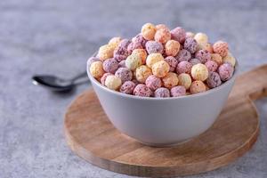 mélange de boules de céréales de maïs colorées, bonbons de bol de saveur de fruits sur fond de ciment gris, gros plan, petit déjeuner frais, délicieux et sain, concept de design d'espace de copie. photo