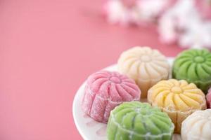 gâteau de lune coloré en peau de neige, gâteau de lune enneigé sucré, dessert salé traditionnel pour le festival de la mi-automne sur fond rose pâle pastel, gros plan, style de vie. photo