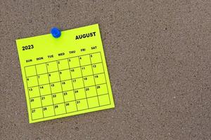 août 2023 calendrier de notes autocollantes jaunes avec épingle sur panneau d'affichage en liège. photo