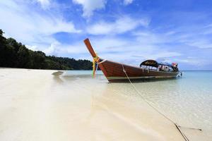 bateau à longue queue sur une plage de sable blanc sur une île tropicale photo