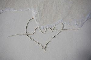 coeurs dessinés sur le sable d'une plage photo