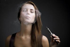 femme élégante, fumer une cigarette électronique avec de la fumée photo