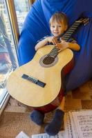 petit garçon joue de la guitare et chante sur le balcon photo