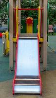 un élément d'une balançoire pour enfants. faire glisser. une aire de jeux extérieure colorée à côté de la maison. un jour d'été. aire de jeux pour enfants avec revêtement de sol en caoutchouc. photo