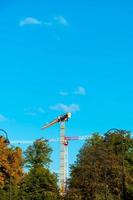 les grues de construction travaillent sur le site de création sur fond de ciel bleu. vue de dessous de la grue industrielle. concept de construction d'immeubles d'appartements et de rénovation de logements. copie espace photo