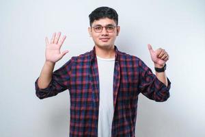 jeune bel homme asiatique portant des vêtements décontractés montrant et pointant vers le haut avec les doigts numéro six tout en souriant confiant et heureux photo