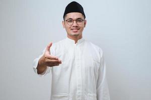 homme musulman asiatique souriant amical offrant une poignée de main comme salutation et accueil. entreprise prospère. photo