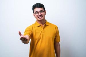 jeune homme asiatique portant des vêtements décontractés souriant amical offrant une poignée de main comme salutation et accueil photo