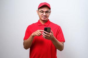 heureux livreur asiatique portant des lunettes tenant et pointant sur le téléphone cellulaire photo