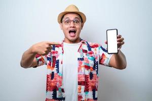 excité jeune homme asiatique choc montrant l'écran du téléphone à la caméra pointant vers l'écran du téléphone blanc photo