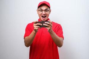 livreur asiatique choqué portant des lunettes tenant et pointant sur le téléphone cellulaire photo
