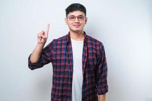 jeune bel homme asiatique portant des vêtements décontractés montrant et pointant vers le haut avec les doigts numéro un tout en souriant confiant et heureux photo