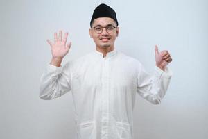 homme musulman asiatique portant des vêtements décontractés montrant et pointant vers le haut avec les doigts numéro six tout en souriant confiant et heureux photo