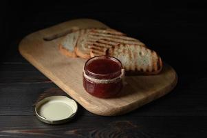 pain grillé avec de la confiture de fraises maison et sur une table rustique avec du beurre pour le petit déjeuner ou le brunch. photo