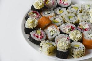 différents rouleaux de riz avec du poisson et du concombre sur une assiette blanche. photo