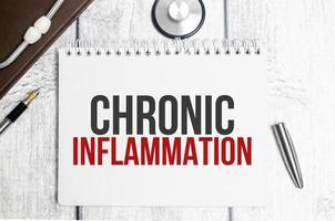 mots d'inflammation chronique sur le bloc-notes et le stéthoscope photo