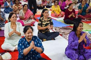 new delhi, inde, 19 juin 2022 - séance d'exercices de yoga en groupe pour les personnes de différents groupes d'âge dans le temple balaji, vivek vihar, journée internationale du yoga, grand groupe d'adultes assistant à un cours de yoga dans le temple photo
