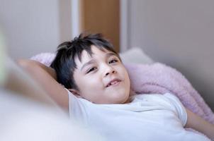 portrait heureux yong garçon allongé sur un canapé se détendre à la maison, coup de tête mignon enfant regardant la caméra avec un visage souriant, enfant positif assis sur un canapé s'amusant le week-end photo