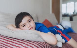 portrait dramatique enfant solitaire visage triste allongé sur un canapé, enfant émotionnel allongé sur un canapé dans le salon avec une réflexion profonde, un jeune garçon s'ennuie à rester seul à la maison. photo