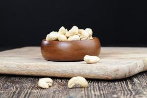 noix de cajou sur une vieille table en bois et dans un bol en bois photo