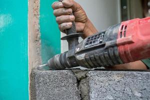 les techniciens utilisent une perceuse pour percer des trous dans la maçonnerie afin de renforcer la structure de la construction. photo