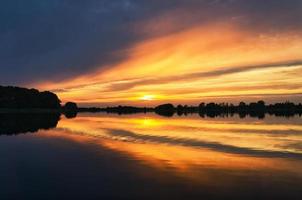 reflet du ciel dans l'eau. les couleurs or, jaune et rose du ciel se reflètent dans le lac. photo