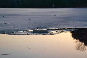 bord de glace sur un lac au coucher du soleil. photo