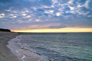 sur la plage de la mer baltique. coucher de soleil, épis, plage et sable. photo de paysage