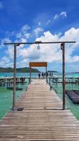 hors-bord ou bateau garé et attendant le groupe de la visite, les personnes ou les touristes à prendre pour un voyage en mer ou en océan avec un ciel bleu, un nuage blanc, une station colorée et un fond de montagne verte. vue beauté photo