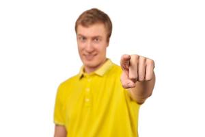 souriant beau mec attrayant en t-shirt jaune décontracté pointant vers l'avant, fond blanc isolé photo