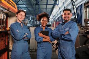 des travailleurs joyeux de l'industrie multiraciale en uniformes de sécurité s'alignent et les bras croisés après le succès du travail et expriment des sourires et du bonheur dans une usine mécanique. profession d'ingénieur professionnel. photo