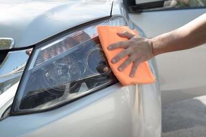 nettoyez manuellement les phares du projecteur de voiture avec un chiffon en microfibre orange. photo