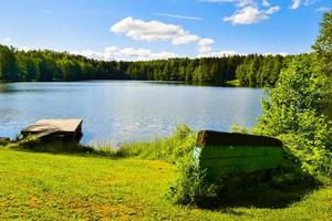 bateaux à l'envers au bord d'un lac bleu calme dans la campagne de lituanie .pêche dans les pays baltes à l'extérieur en été photo