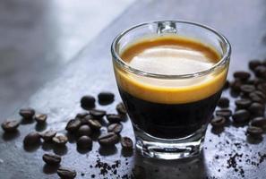 tasse d'espresso chaud avec une belle crème sur une table en béton rustique avec un tas de café arabica torréfié. photo