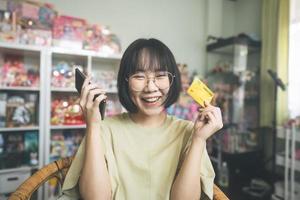 une jeune femme asiatique adulte utilisant un smartphone et une carte de crédit effectue une transaction via une application numérique photo