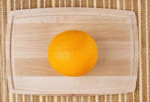 une orange juteuse sur une planche à découper en bois. photo