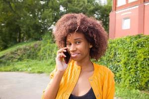 la femme afro-américaine heureuse dans la rue parlant au téléphone