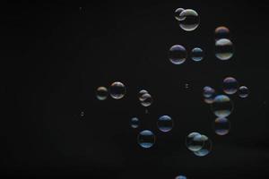 bulles de savon volantes sur fond noir. bulles de savon abstraites aux reflets colorés. bulles de savon en arrière-plan de mouvement. photo