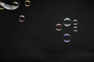 bulles de savon volantes sur fond noir. bulles de savon abstraites aux reflets colorés. bulles de savon en arrière-plan de mouvement. photo