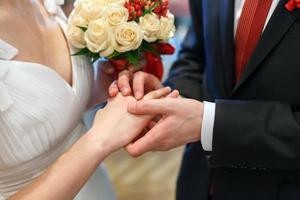 le marié embrasse la mariée avec un bouquet de mariée. anneaux sur les mains du couple nouvellement marié. mariée posa ses mains sur les épaules du marié. photo