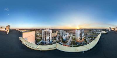 panorama sphérique complet et harmonieux aérien vue à 360 degrés depuis le toit d'un immeuble à plusieurs étages avec vue sur le quartier résidentiel au coucher du soleil en projection équirectangulaire. photo