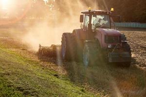 le cultivateur de tracteur laboure la terre, se prépare pour les cultures. poussière sur le terrain photo