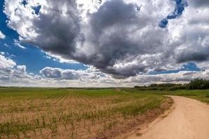 vue panoramique sur la route serpentine sablonneuse laissant au loin et de beaux nuages photo