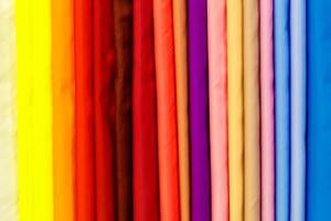 Large sélection de vêtements de tissus de soie textile de couleur différente en rangée dans un magasin de draperies photo