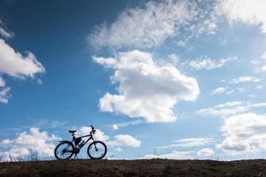 silhouette de vélo dans un ciel bleu avec des nuages. symbole d'indépendance et de liberté photo